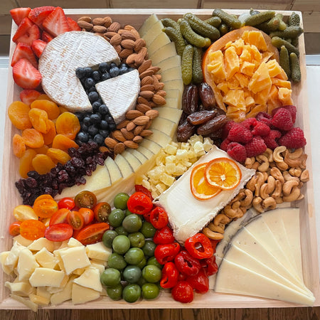 Image is a top view of the Signature Cheese Platter with olives, nuts, fresh and dried fruit and additional accoutrements. 