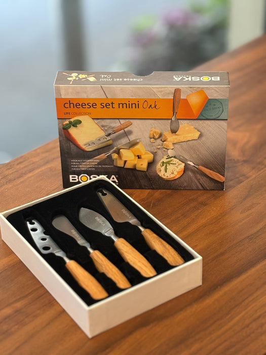 Image is of an open set of the boska mini cheese knives on a WOODEN TABLE. 